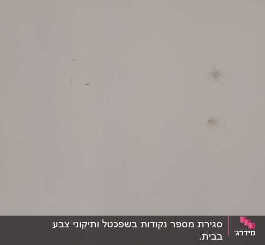 קיר לבן עם חורים קטנים וכתמים